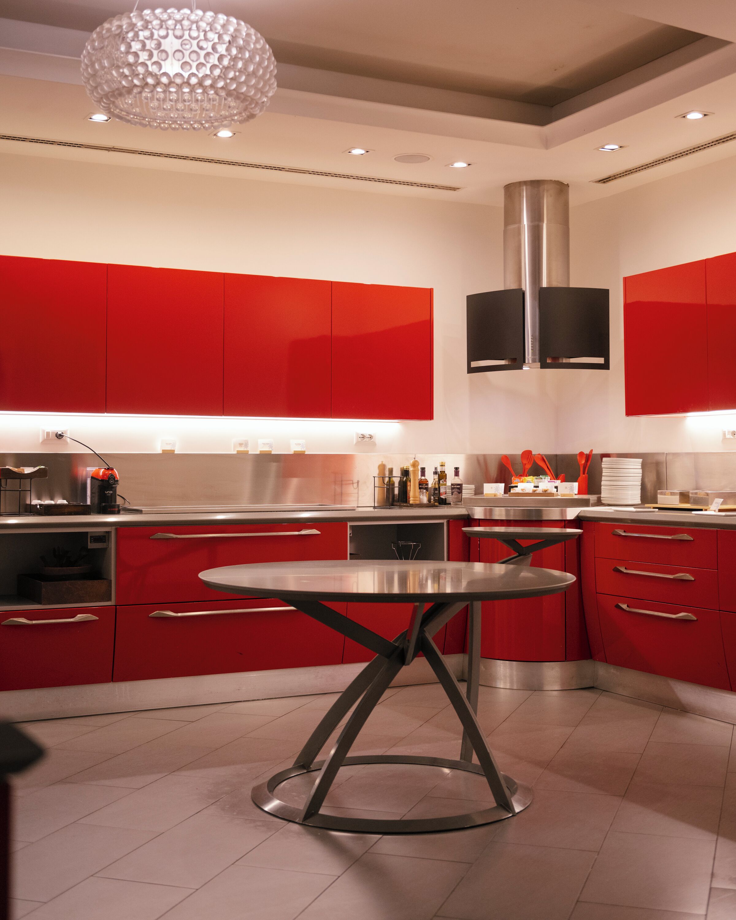 Une cuisine moderne avec des meubles de rangement rouges, des appareils en acier inoxydable et un îlot central.