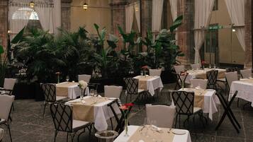 Un ristorante con tavoli rotondi, sedie e piante in vaso.