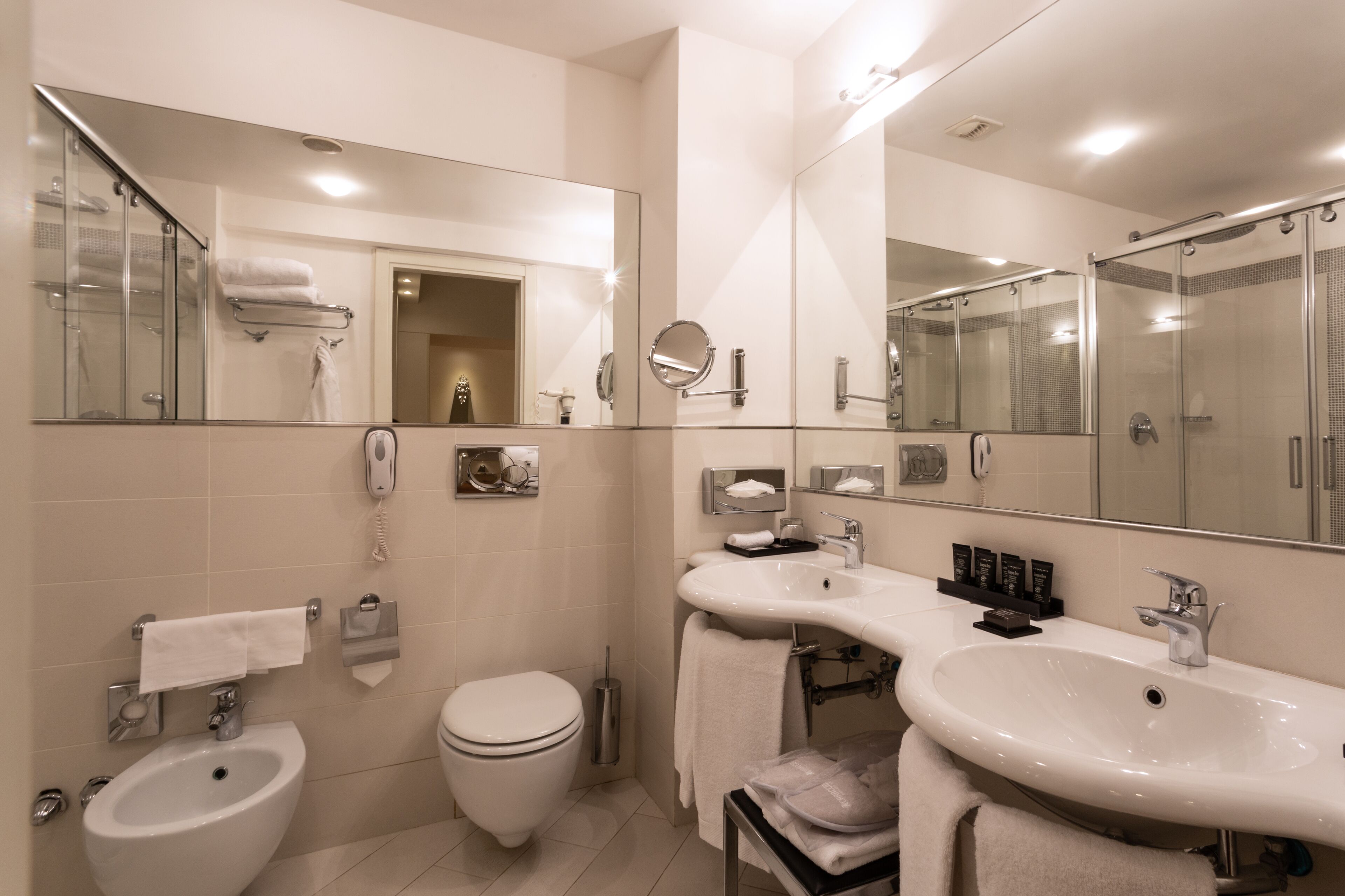 Une salle de bain moderne équipée d’un bidet, de toilettes et de deux lavabos.