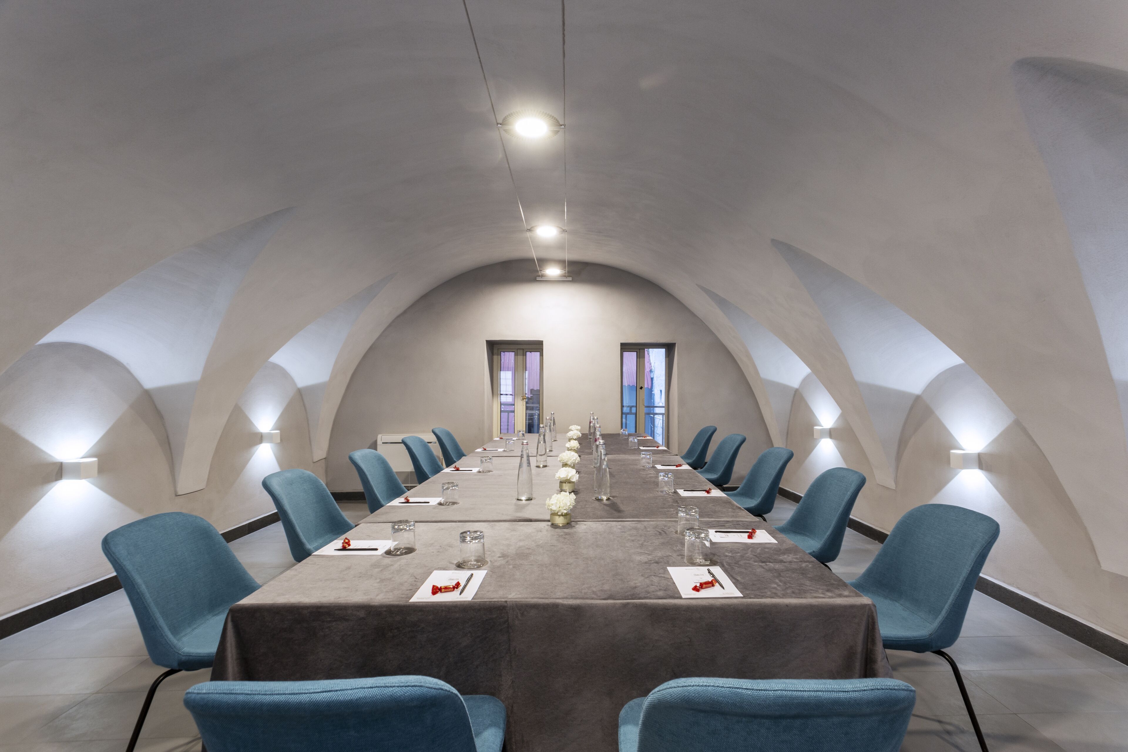 A conference room with a long table, blue chairs, and a modern ceiling design.