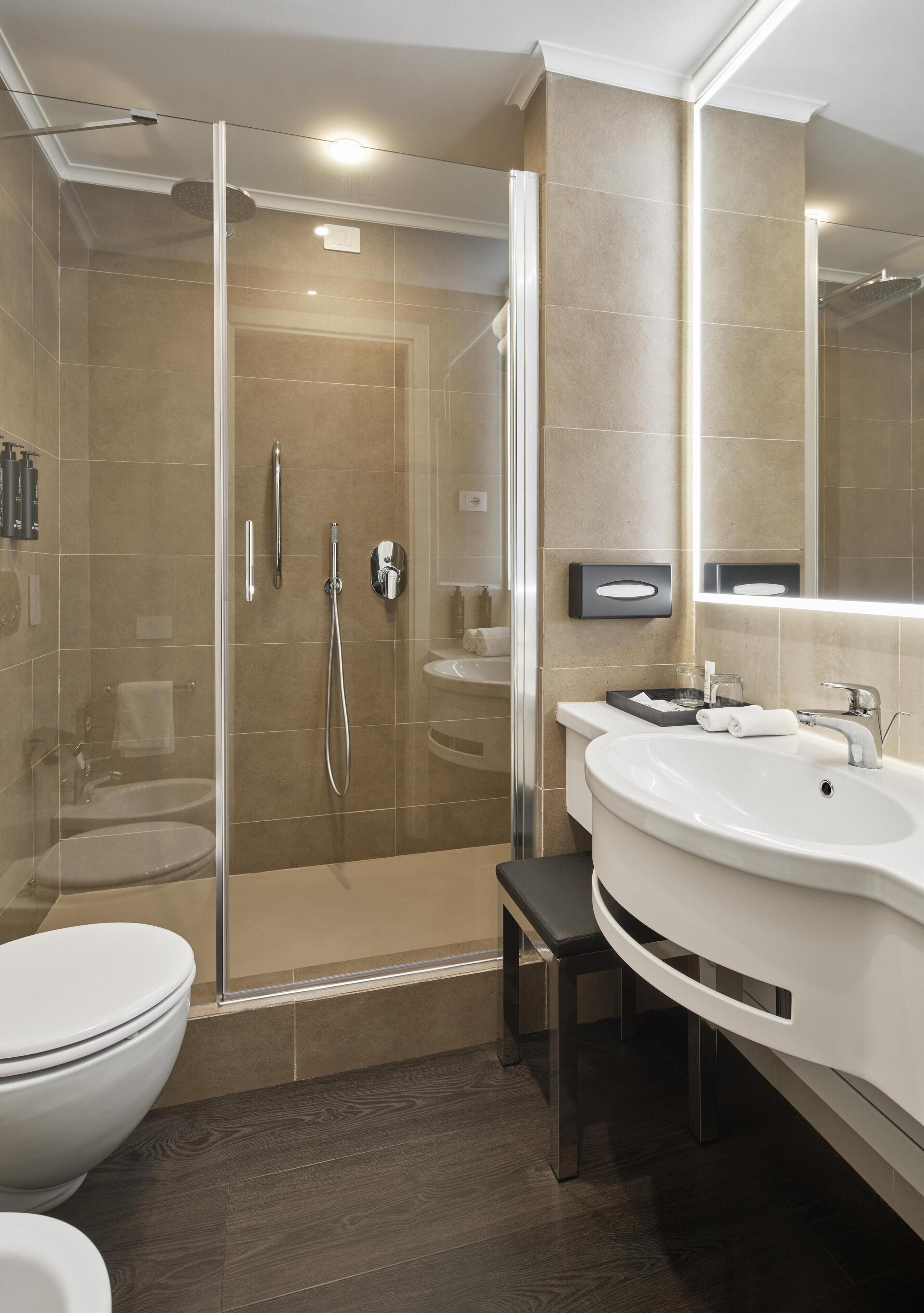 Ein modernes Badezimmer mit einer gläsernen Duschkabine, einem weißen Waschbecken und einer Toilette.