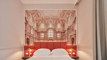 A bedroom with a large bed, two bedside tables with lamps, and a mural of a building's interior on the wall.