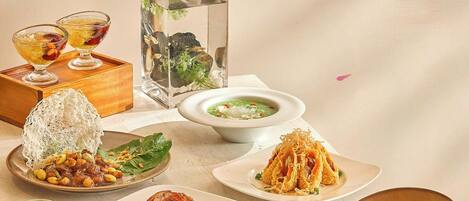 A table with various dishes, a bonsai tree, and a decorative painting of cherry blossoms.