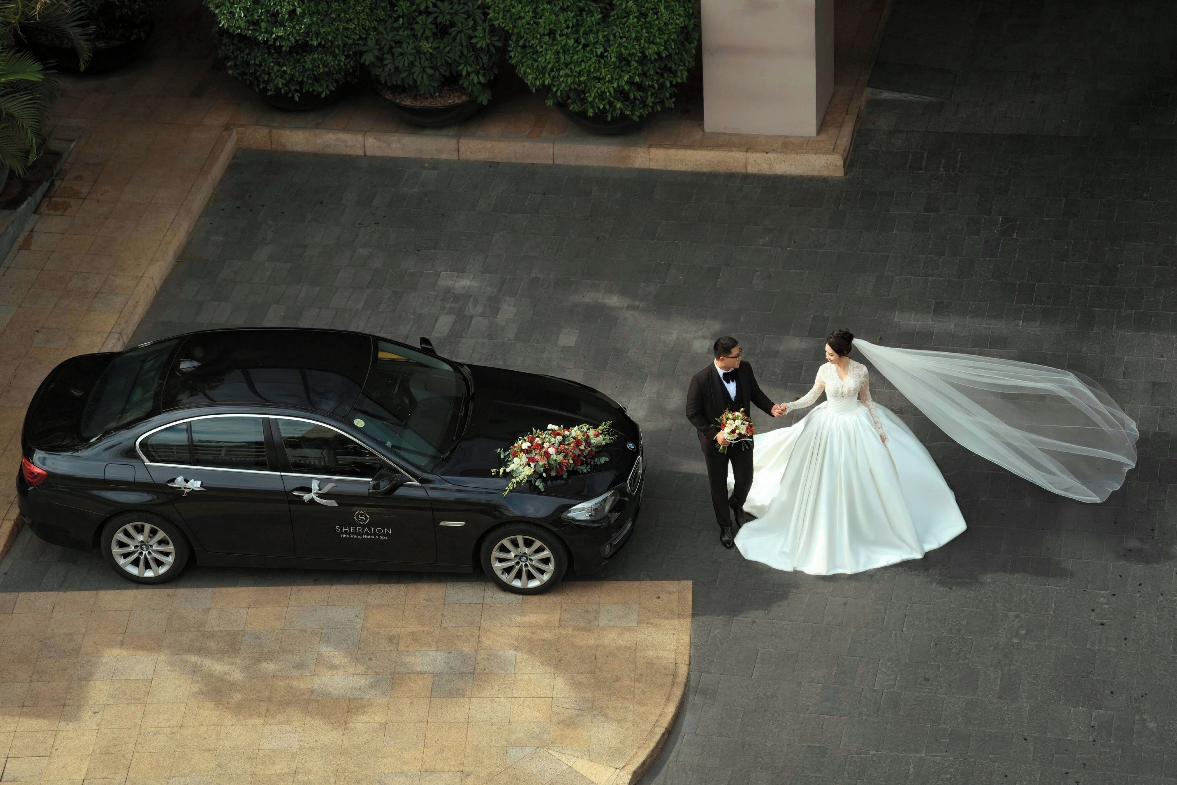A black car parked on a paved area with a building in the background.