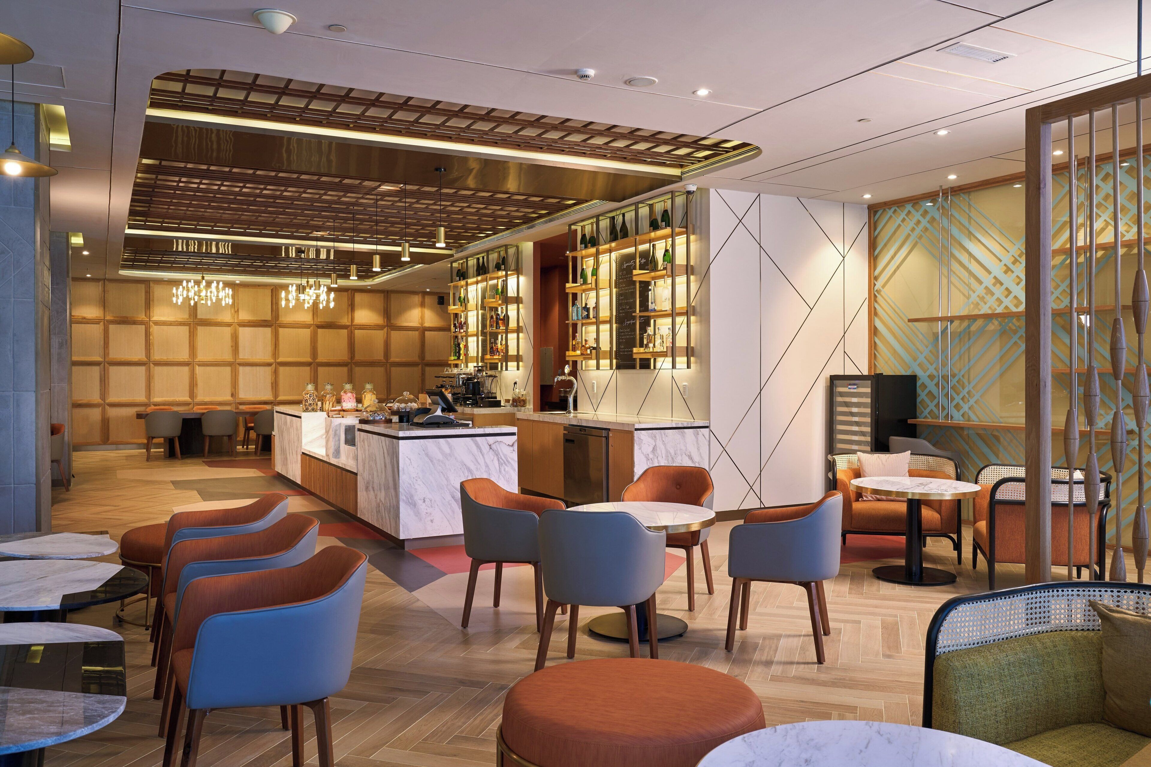 A modern restaurant with a bar area, seating arrangements, and a decorative wall with a geometric pattern.