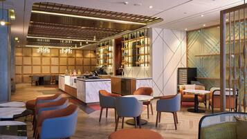 A modern restaurant with a bar area, seating arrangements, and a decorative wall with a geometric pattern.
