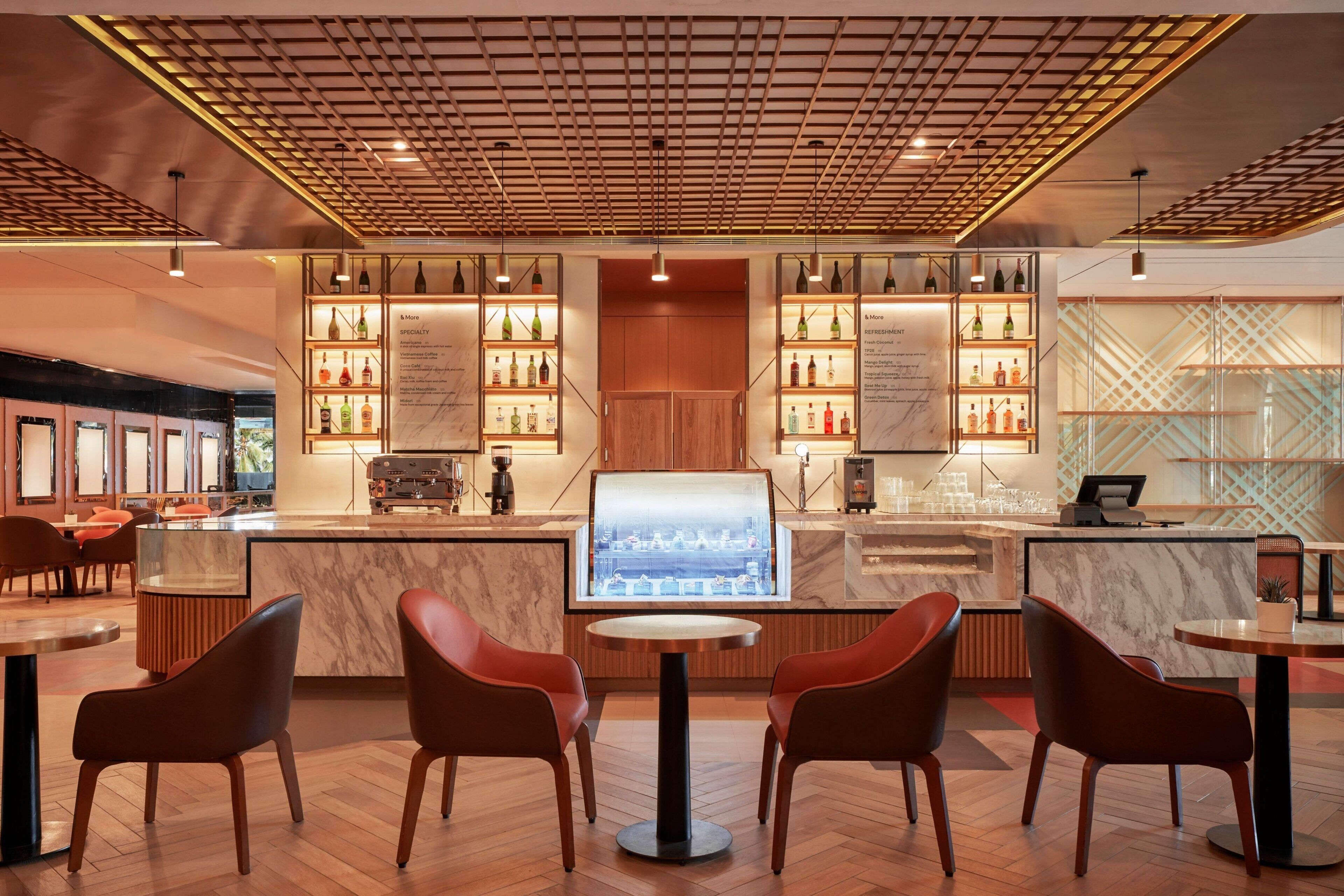 A modern bar area with a central counter, multiple seating options, and a display of bottles.