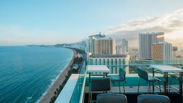 A high-rise hotel with a terrace overlooking a beach and ocean.