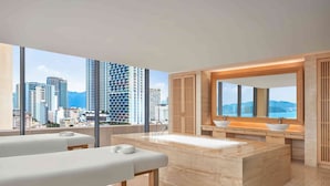 Un baño moderno con un ventanal grande, un lavamanos central y una camilla de masaje.