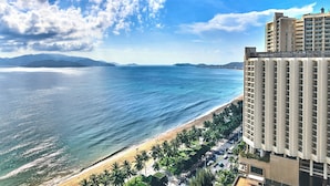 Un hotel costero con vistas a la playa, zona de estacionamiento y camino de acceso a la orilla.