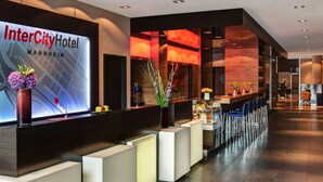 Un vestíbulo de hotel moderno con mostrador de recepción, zona de estar y una gran pantalla digital.