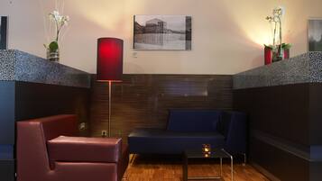 A modern lounge area with a sofa, a chair, a floor lamp, and a small table.