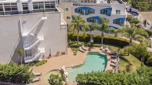 A hotel with a swimming pool, outdoor seating, and a view of the sea.