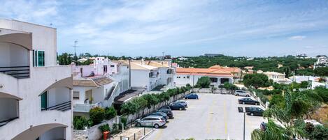 A residential area with a parking lot, multiple-story buildings, and a view of the surrounding landscape.