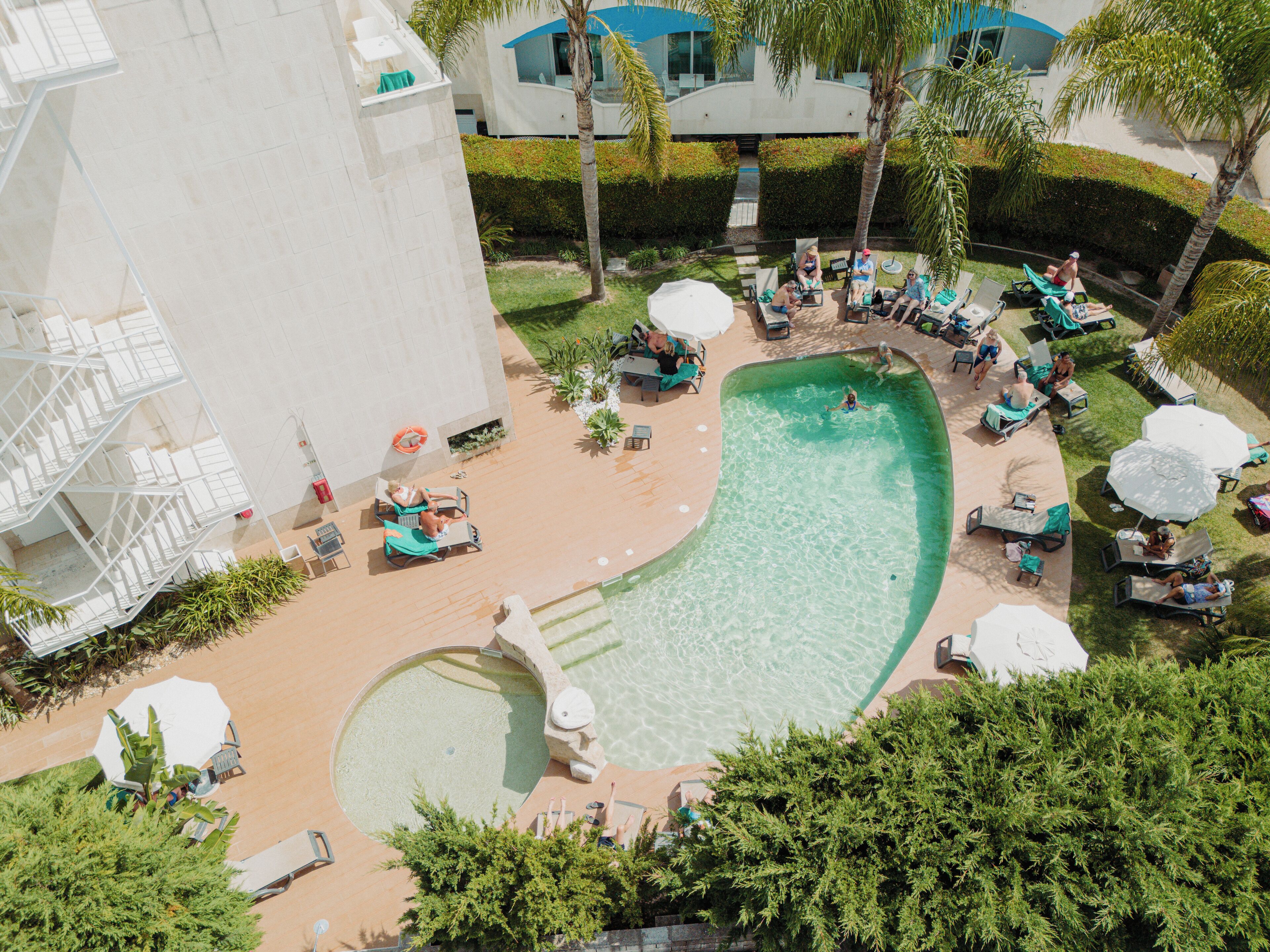 Una piscina al aire libre, sombrillas, tumbonas