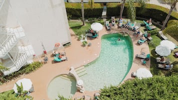 Una piscina al aire libre, sombrillas, tumbonas