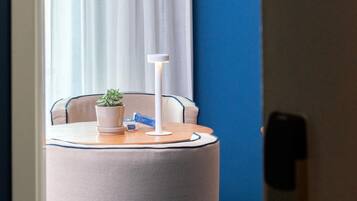 A small round table with a potted plant, a white lamp, and a remote control.
