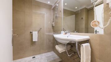 Une salle de bain moderne avec une douche à parois de verre, un lavabo blanc et un grand miroir.