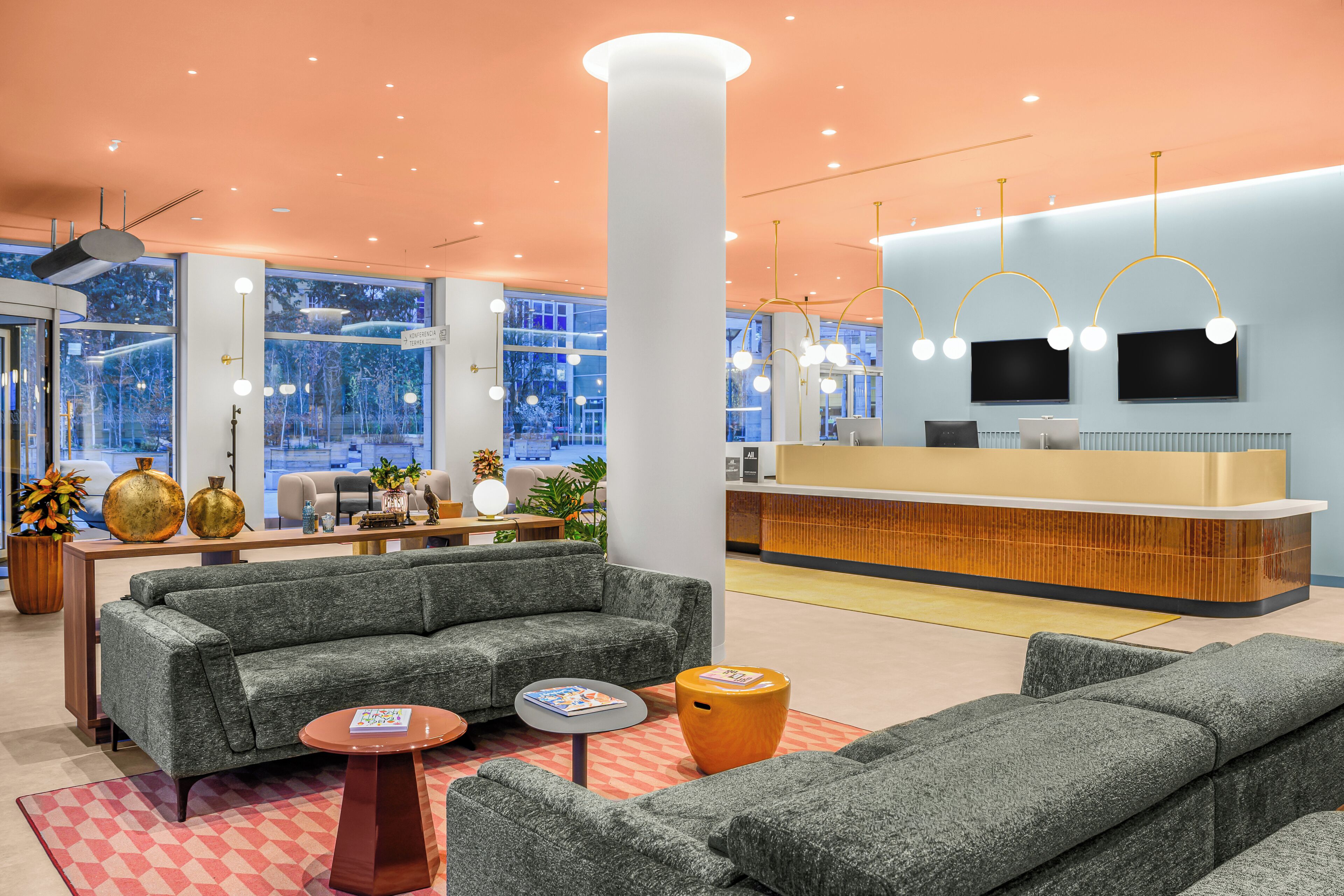 En moderne lobby med grå sofaer, et receptionsskrank og et stort vindue med udsigt til det fri.