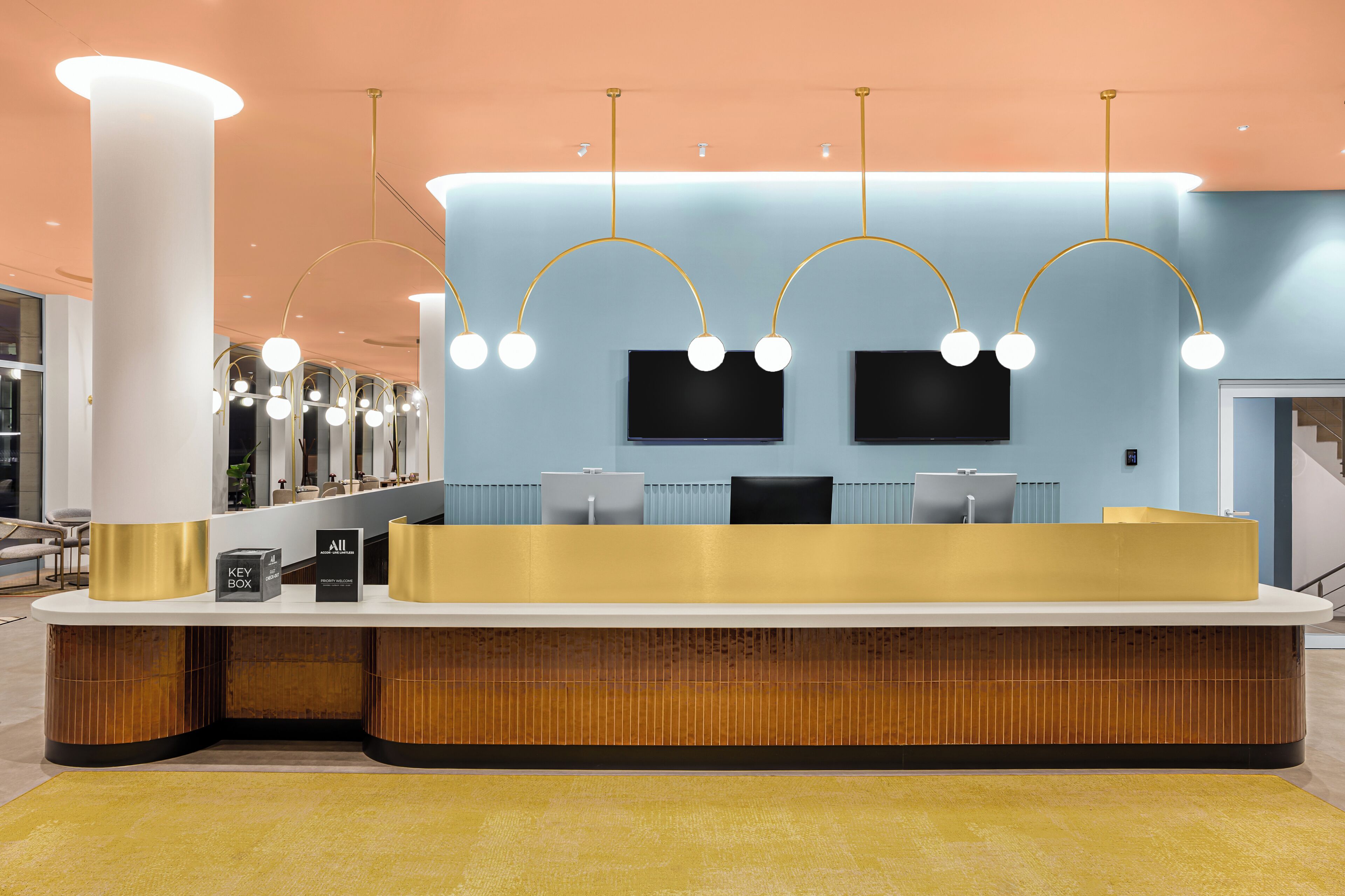 A reception desk with a modern design, featuring a curved counter, a key box, and a small seating area.