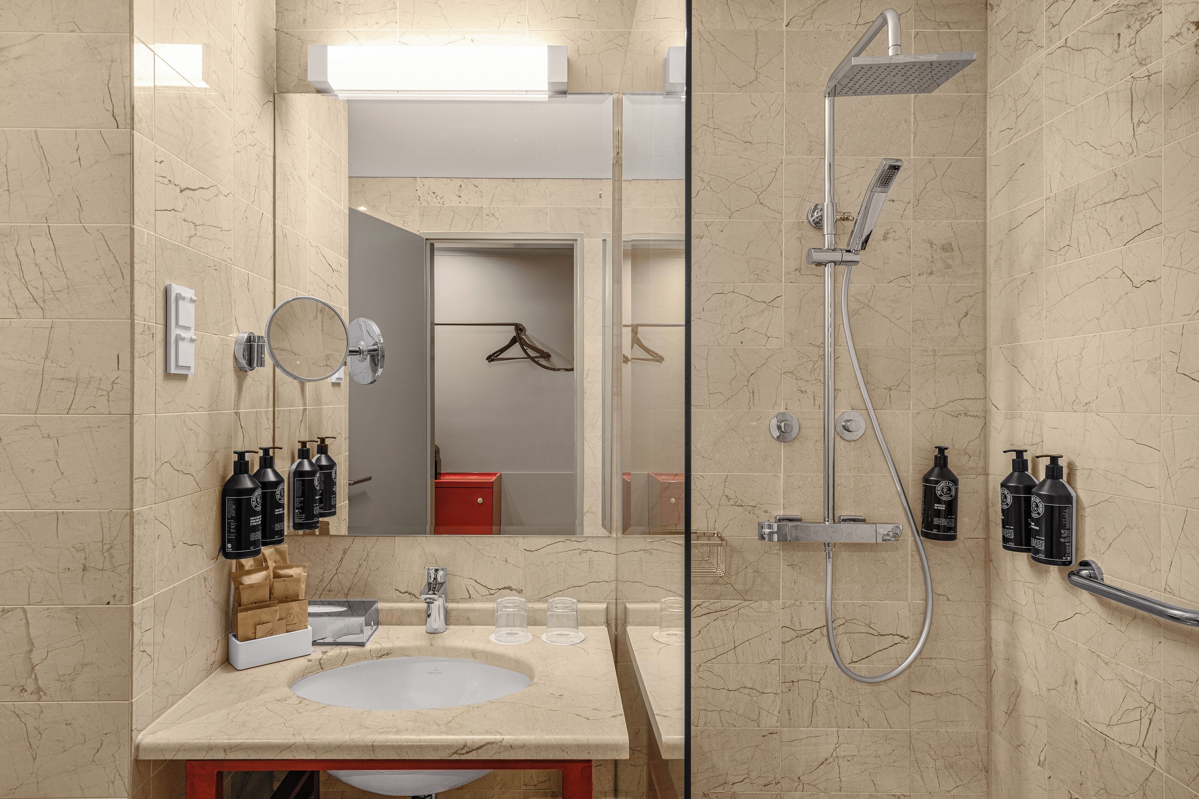 Ein modernes Badezimmer mit Marmorwaschbecken, einer Handbrause und Pflegeprodukten an der Wand.
