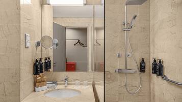 A modern bathroom with a marble sink, a handheld showerhead, and toiletries on the wall.