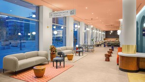 A modern hotel lobby with a large seating area, a reception desk, and a sign indicating conference rooms. - Hotel Lycium Debrecen - Handwritten Collection (Debrecen)