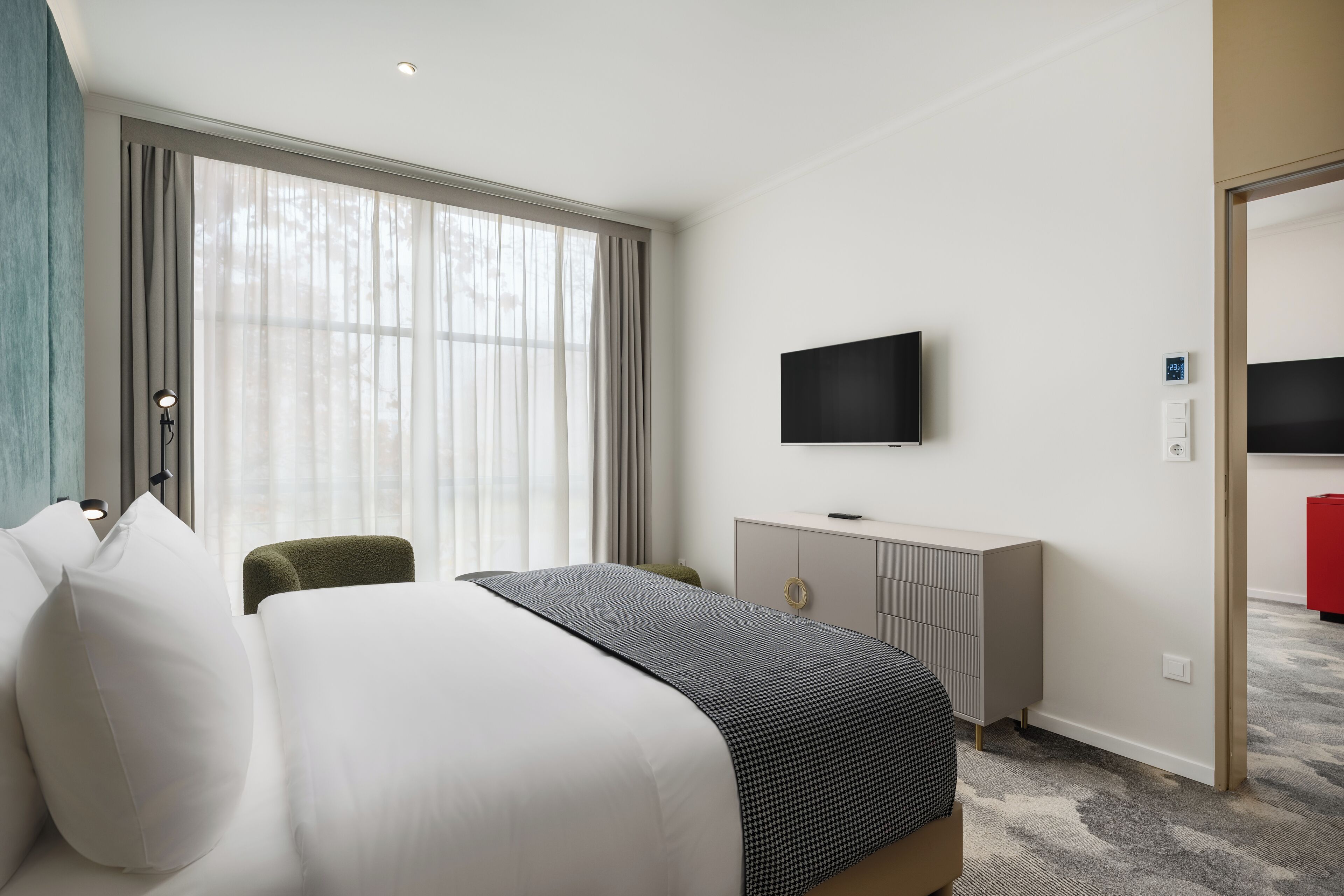 Habitación de hotel con una cama grande, un escritorio, televisión y vistas al exterior.