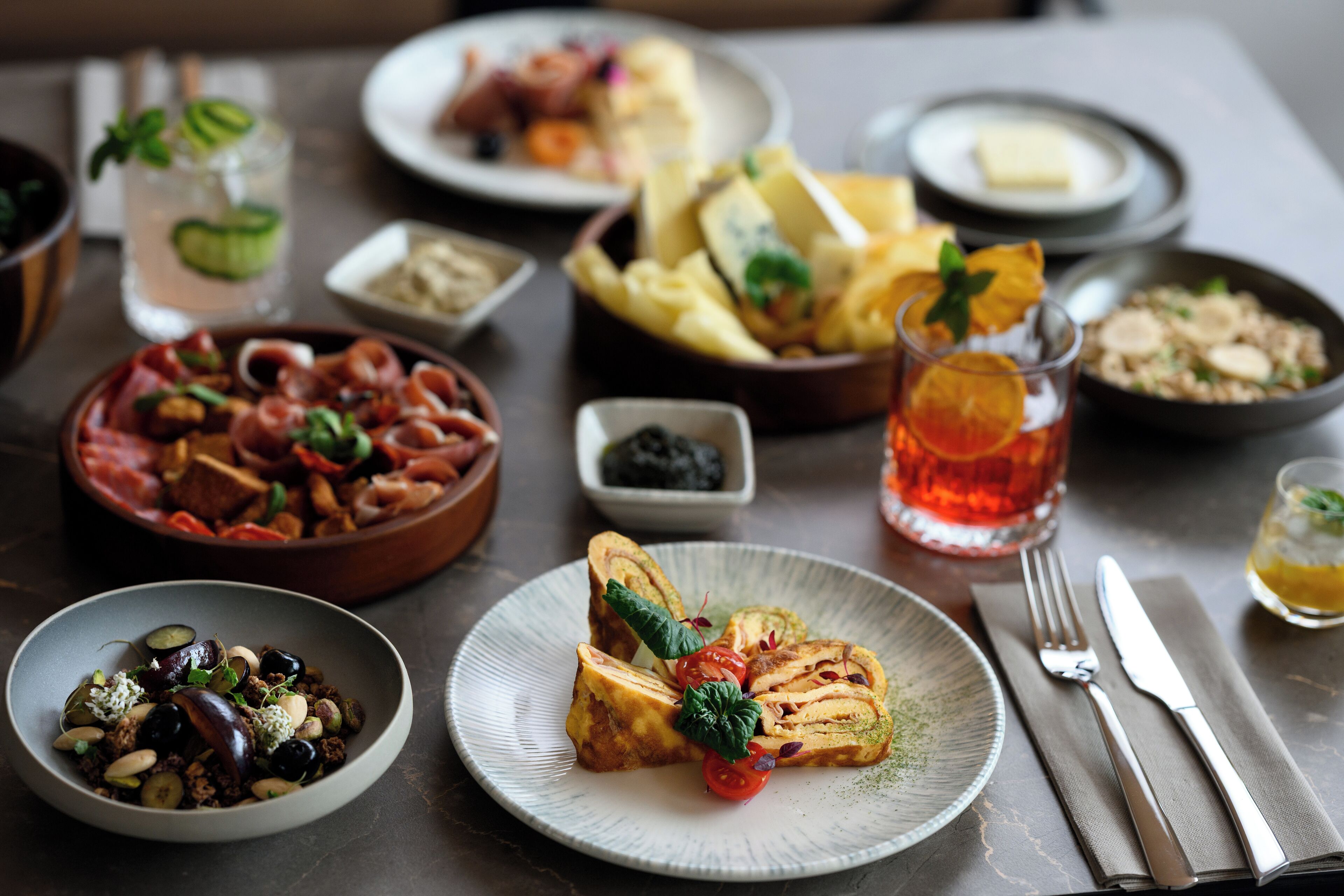 A table set with various dishes, including a bowl of salad, a plate of bread, and a glass of iced tea.