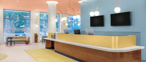A modern reception area with a curved reception desk, two flat-screen TVs, and a large window with a view of trees.