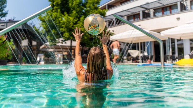 Une personne dans une piscine, avec une fontaine ou un élément décoratif aquatique au-dessus d’elle.