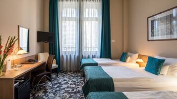 Une chambre d’hôtel avec deux lits, un bureau, une chaise, une télévision et une fenêtre avec des rideaux.