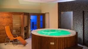 Une pièce avec un mur en bois, une chaise en bois, un jacuzzi rond et une porte.