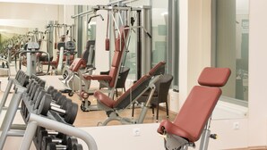 Une salle de sport équipée de divers appareils d’exercice et d’un banc.