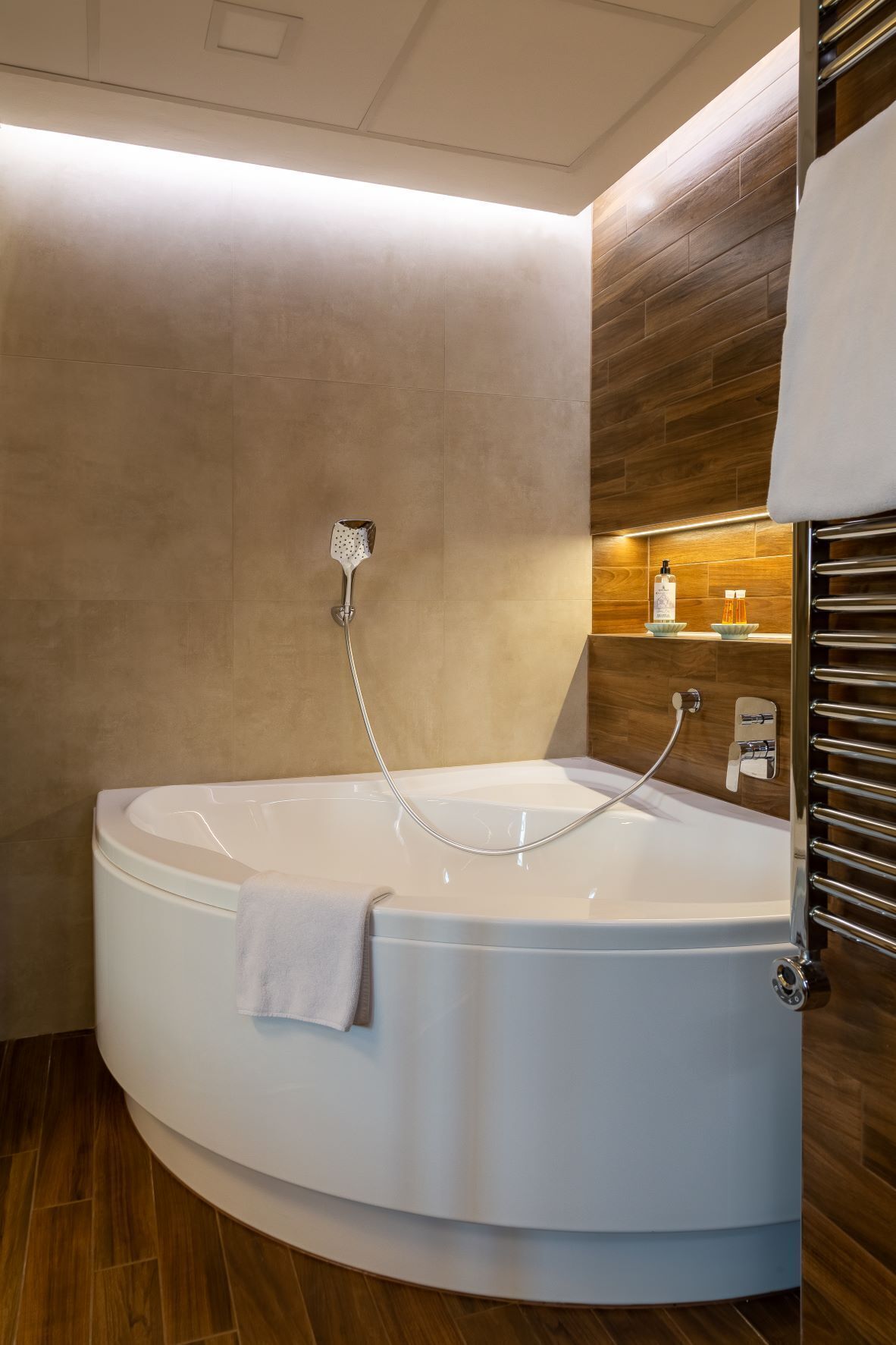 A modern bathroom with a freestanding bathtub, a towel rack, and a wooden wall.