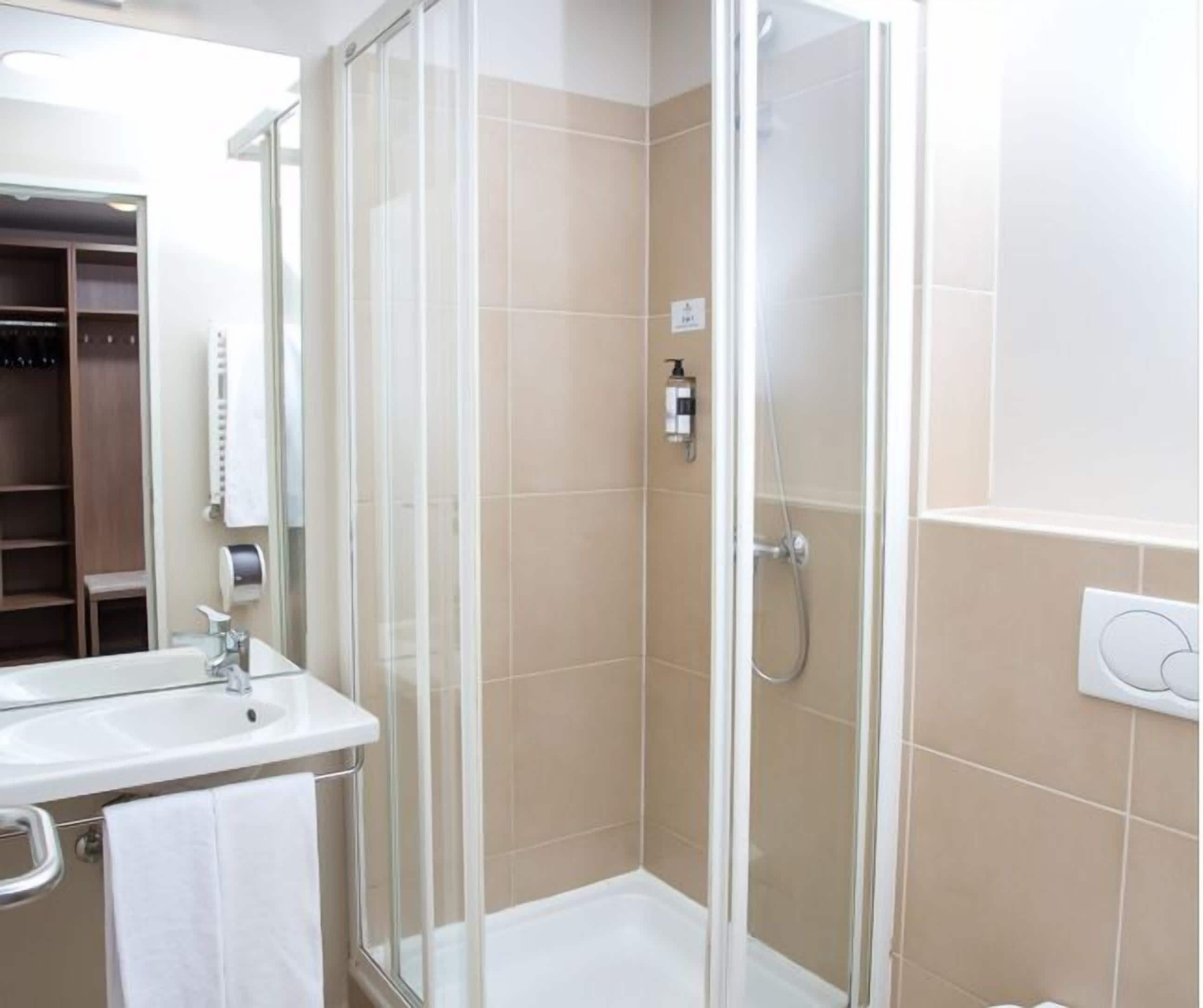 A modern bathroom with a glass-enclosed shower, a sink, and a mirror.