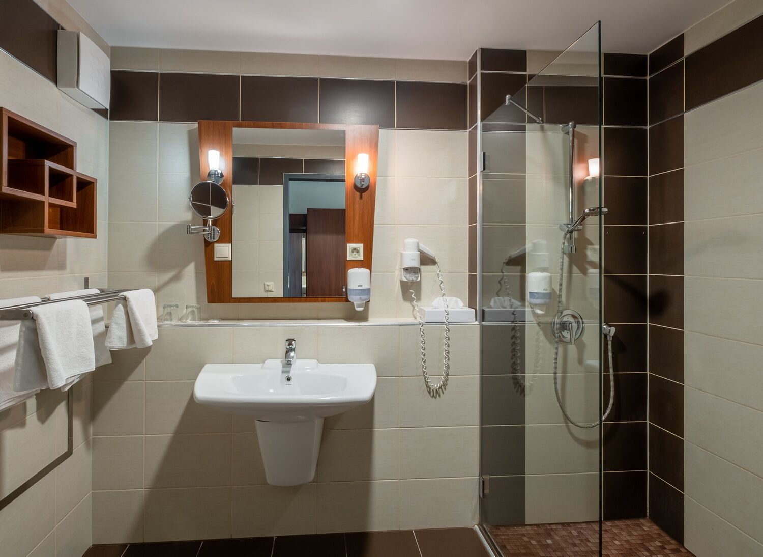 Un baño moderno con lavamanos, espejo y ducha con cerramiento de vidrio.