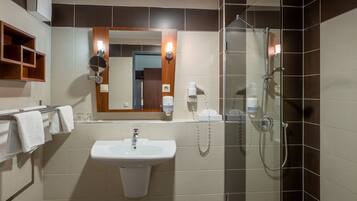 Un baño moderno con lavamanos, espejo y ducha con cerramiento de vidrio.