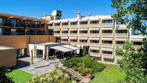 Et hotel med flere balkoner, et overdækket udendørs opholdsområde og en velanlagt have.