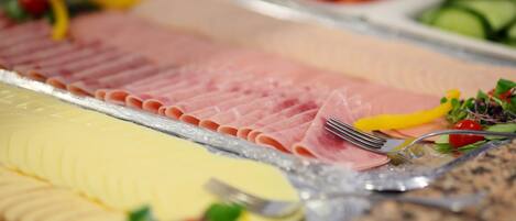 Un bufé con diversos alimentos, incluyendo carnes en rodajas y una ensalada.