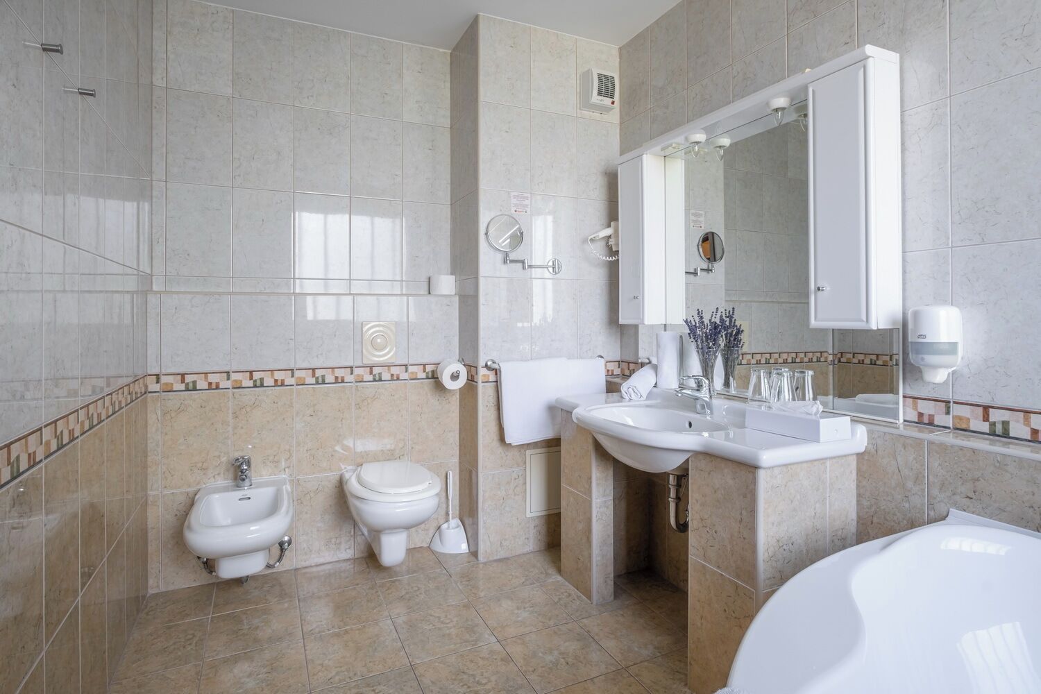 Un baño moderno con una bañera, dos inodoros, un lavabo y un espejo.