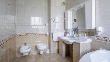 Un baño moderno con una bañera, dos inodoros, un lavabo y un espejo.