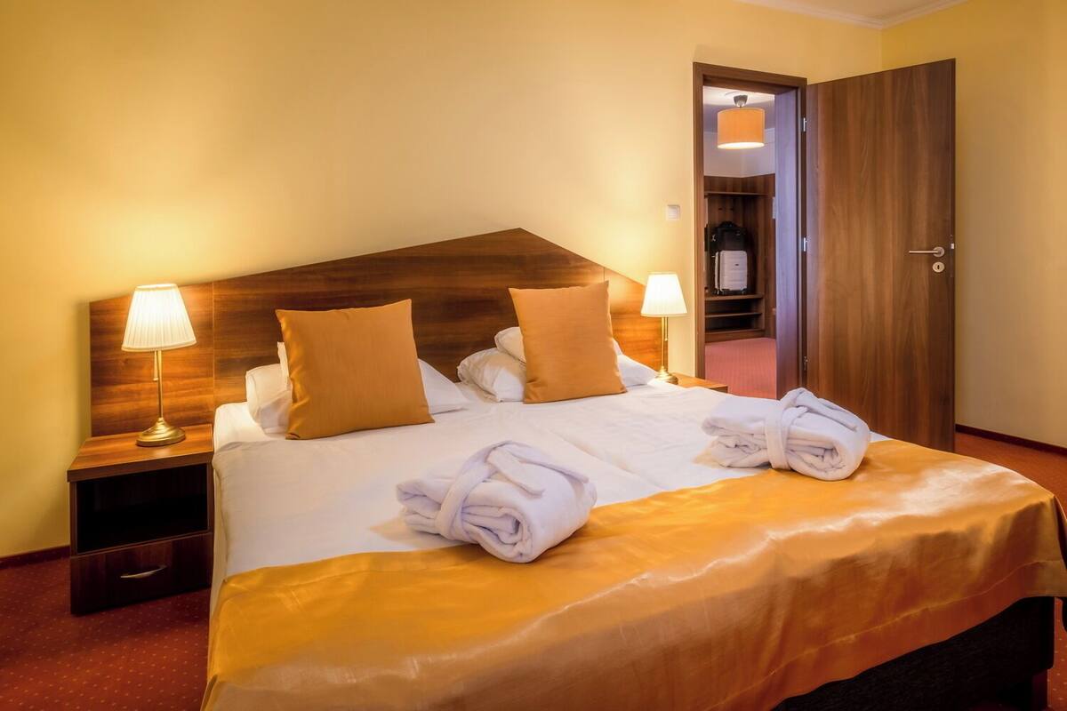 Une chambre d’hôtel avec un grand lit, deux lampes de chevet, une tête de lit en bois et une armoire.