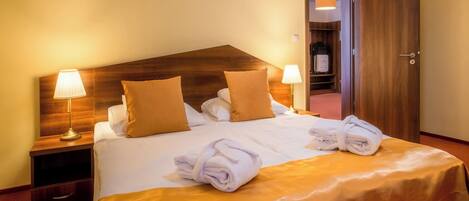 A hotel room with a large bed, two bedside lamps, a wooden headboard, and a wardrobe.
