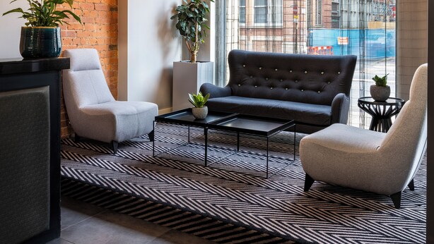 Una sala de estar moderna con un sofá, sillones, una mesa de centro e iluminación colgante.