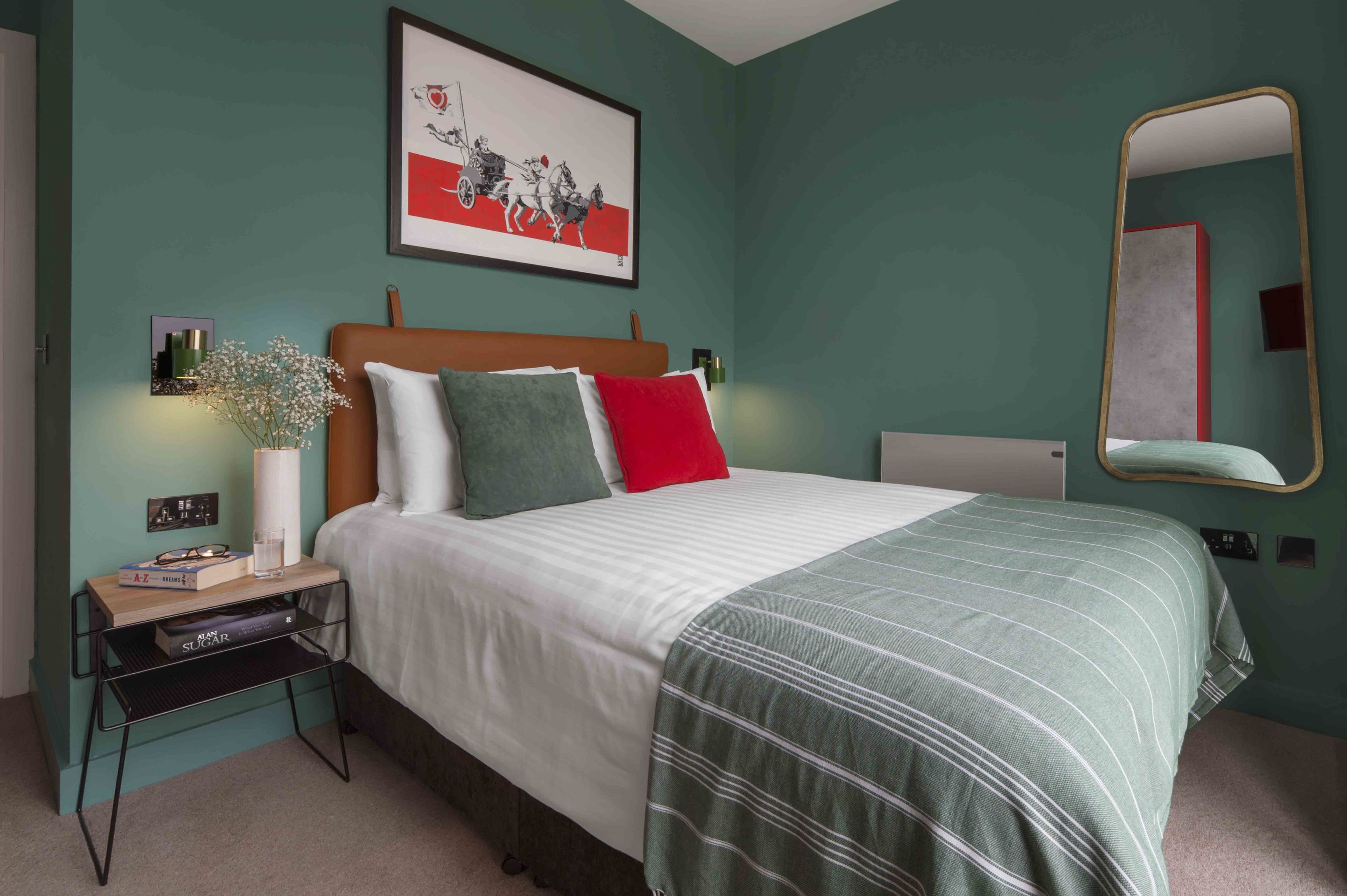 Une chambre à coucher bien rangée, avec un lit, une table de chevet et un grand miroir.