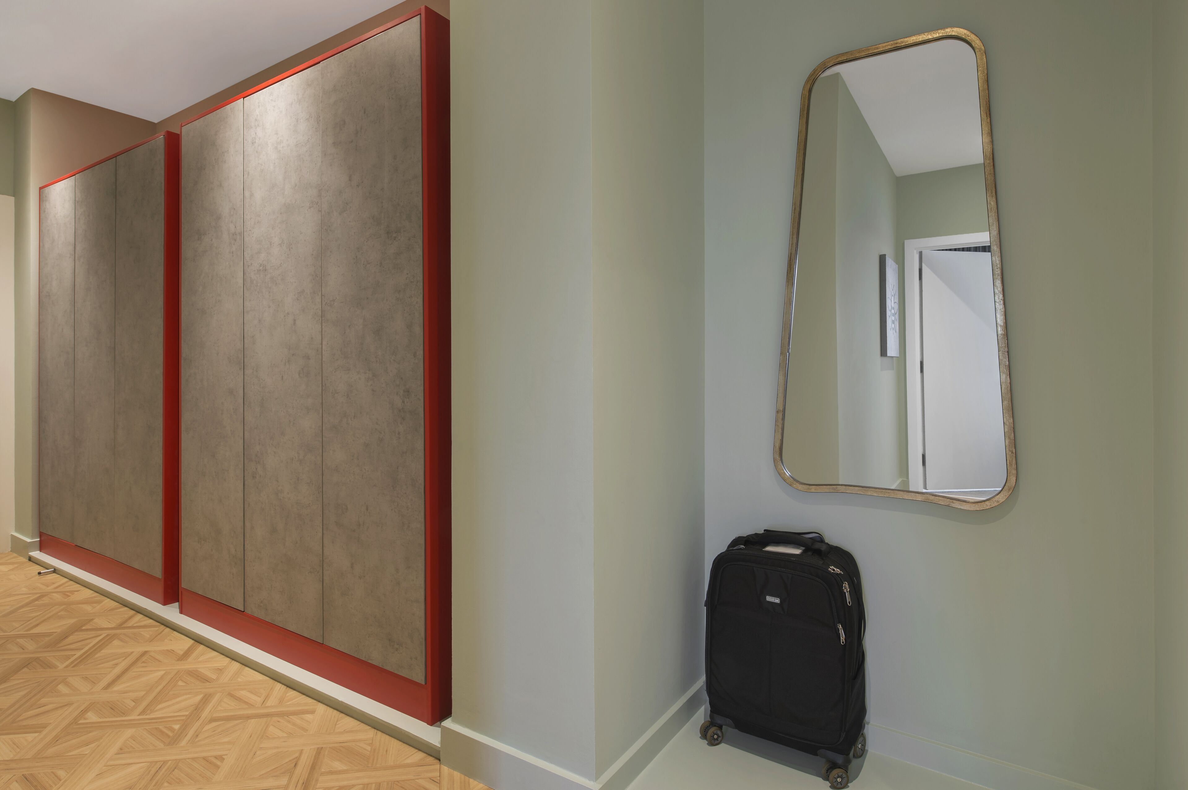 A hallway with a large wardrobe, a mirror, and a suitcase.