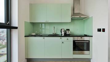 A modern kitchen with light green cabinets, a Bosch oven, and a window overlooking a cityscape.