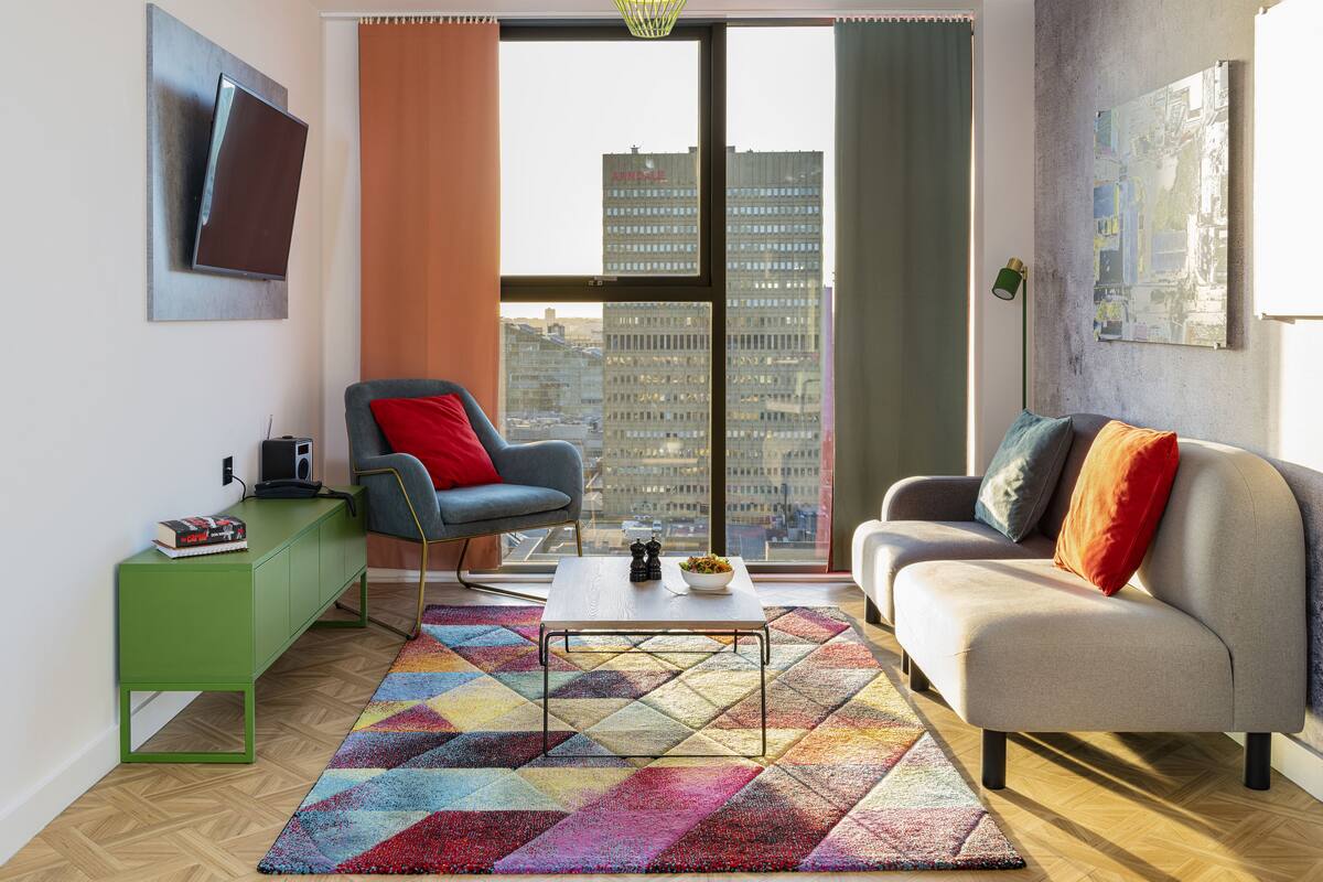 Una sala de estar moderna con un sofá, un sillón, una mesa de centro y una alfombra colorida.