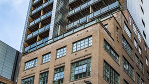 Un edificio de gran altura con varios pisos, ventanas amplias y un diseño arquitectónico moderno.